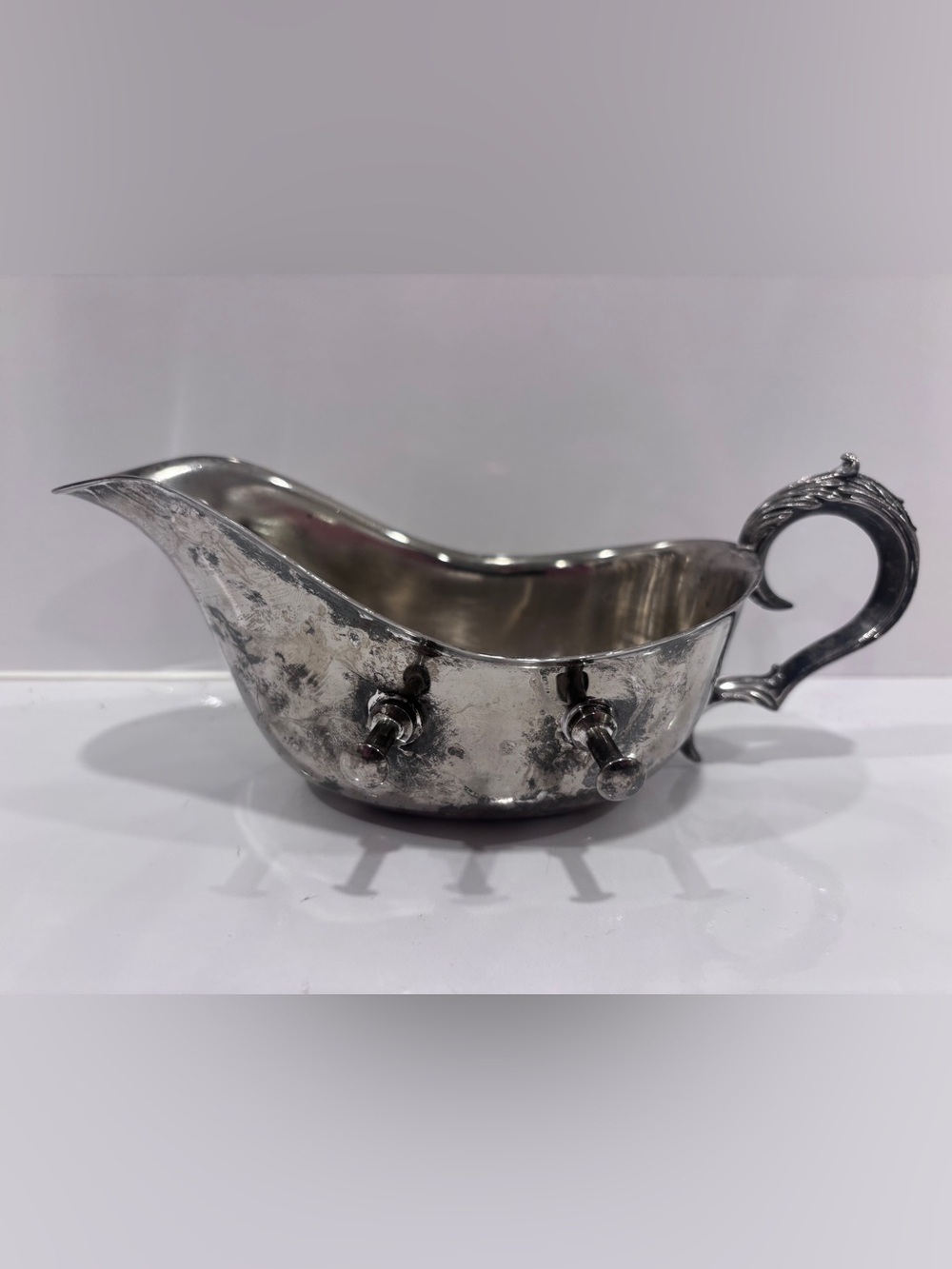 silver-plated gravy boat or sauce server on an integrated warming stand